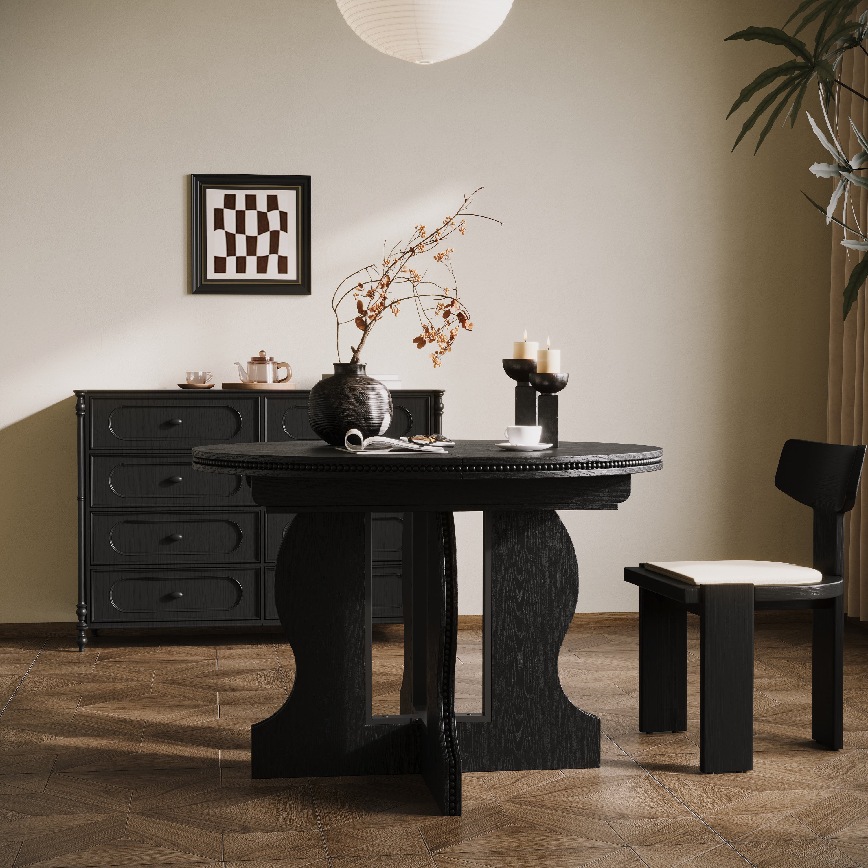 Black round pedestal dining table styled against a wall with a single chair and framed art