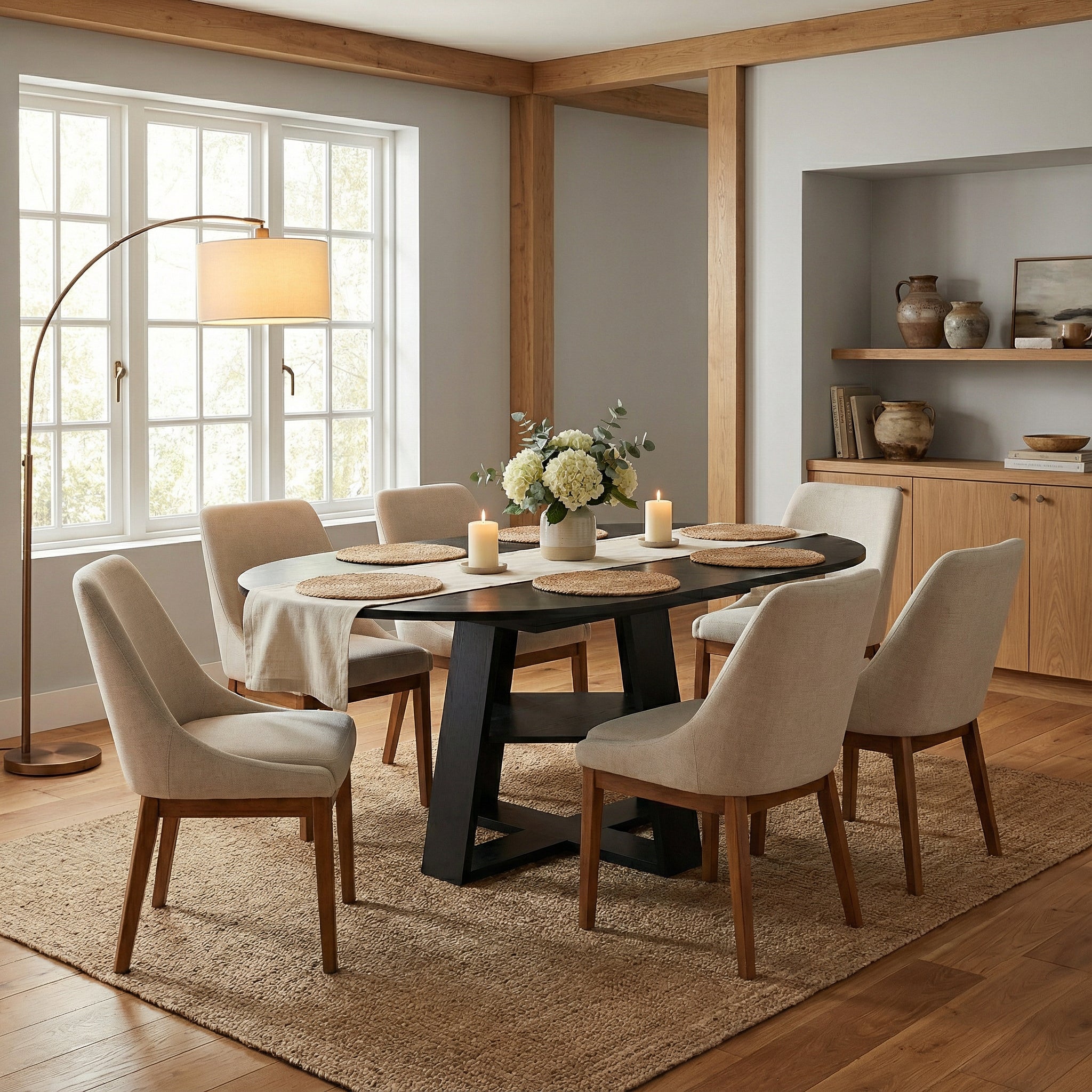 Styled dining room with the black table extended to an oval and six cream chairs