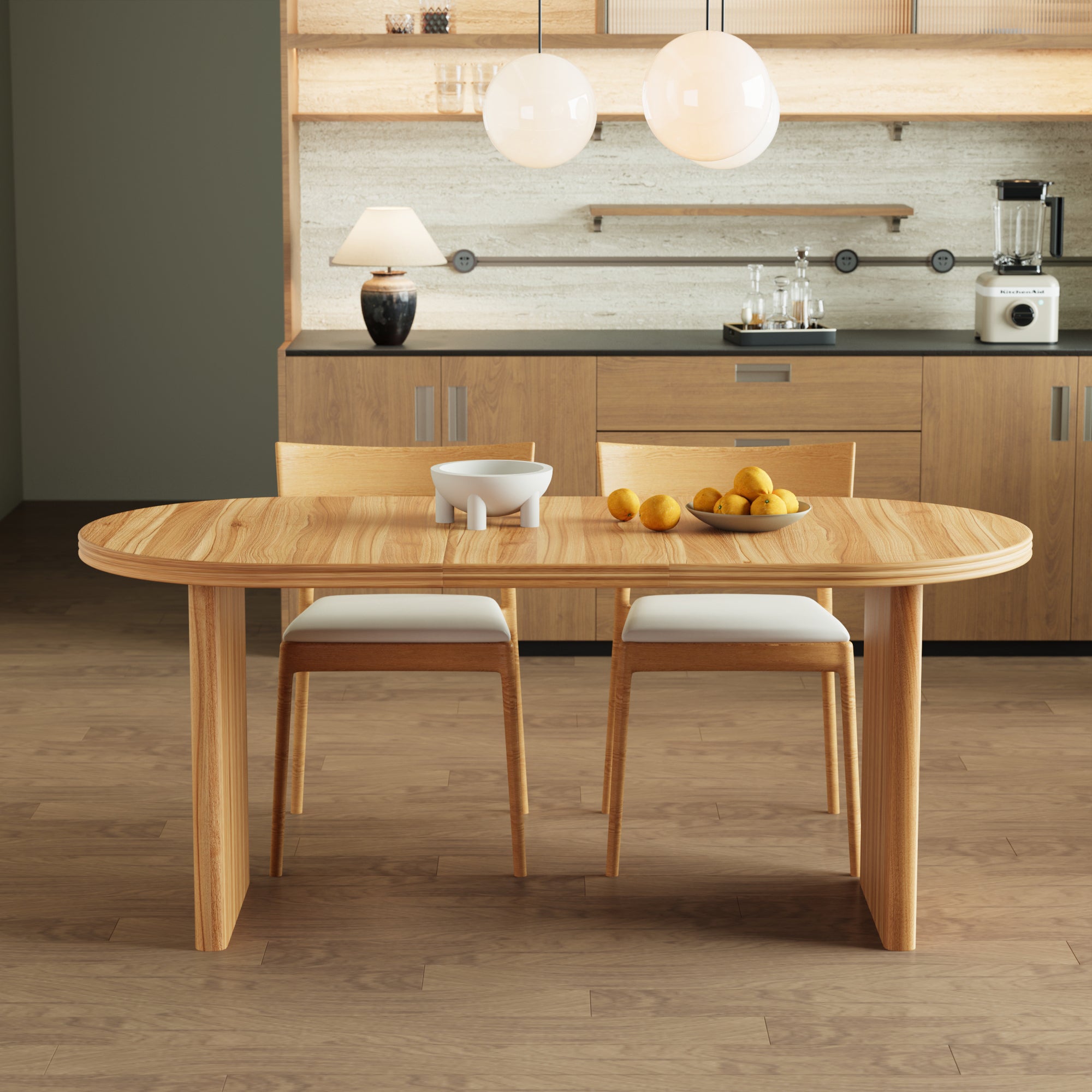 Extended walnut-tone oval dining table with two wood chairs by a kitchen credenza