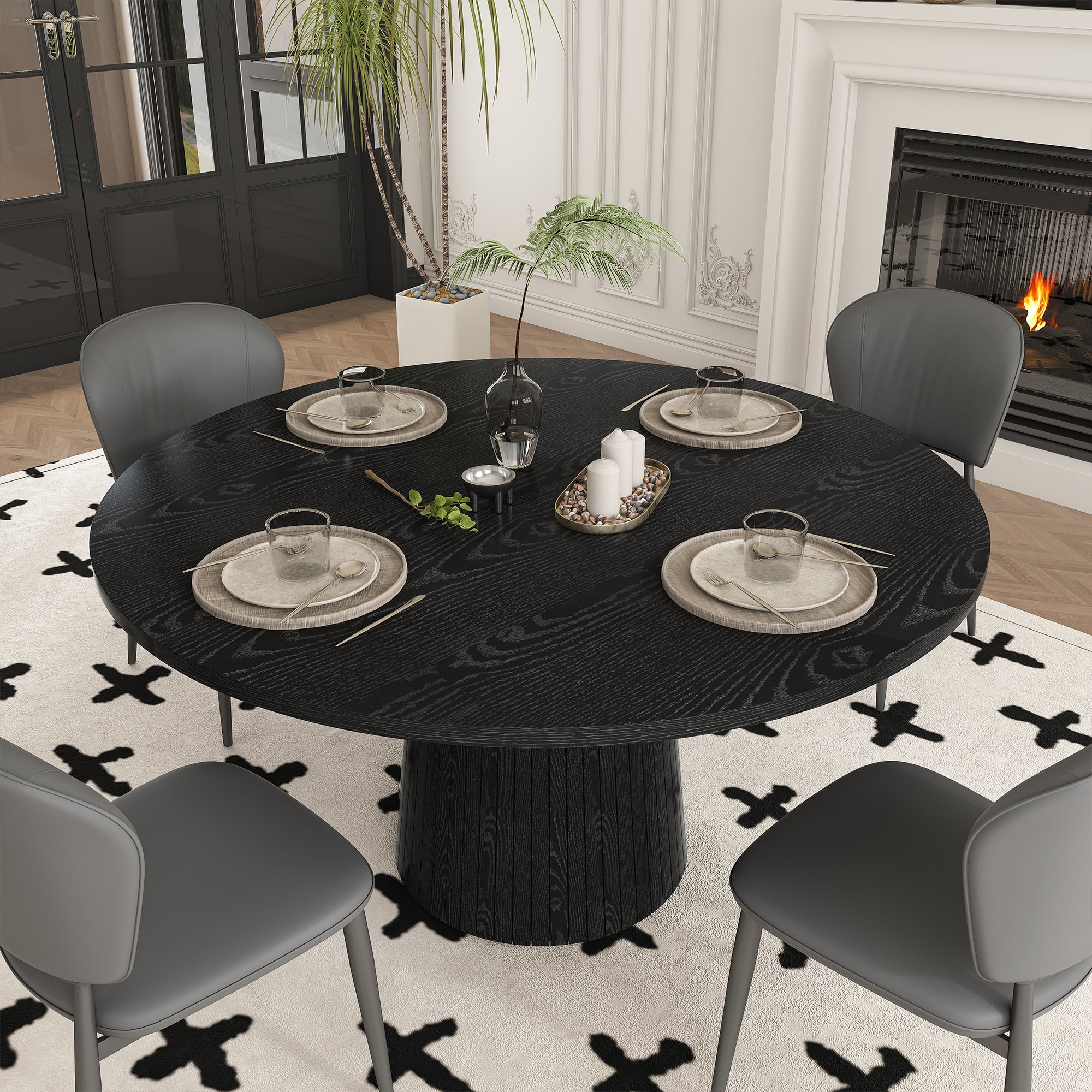 High angle of black round dining table set for four with gray chairs near a fireplace