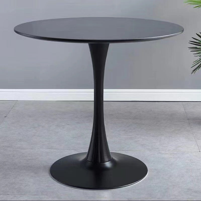 Round black tulip table, front view against a plain gray wall