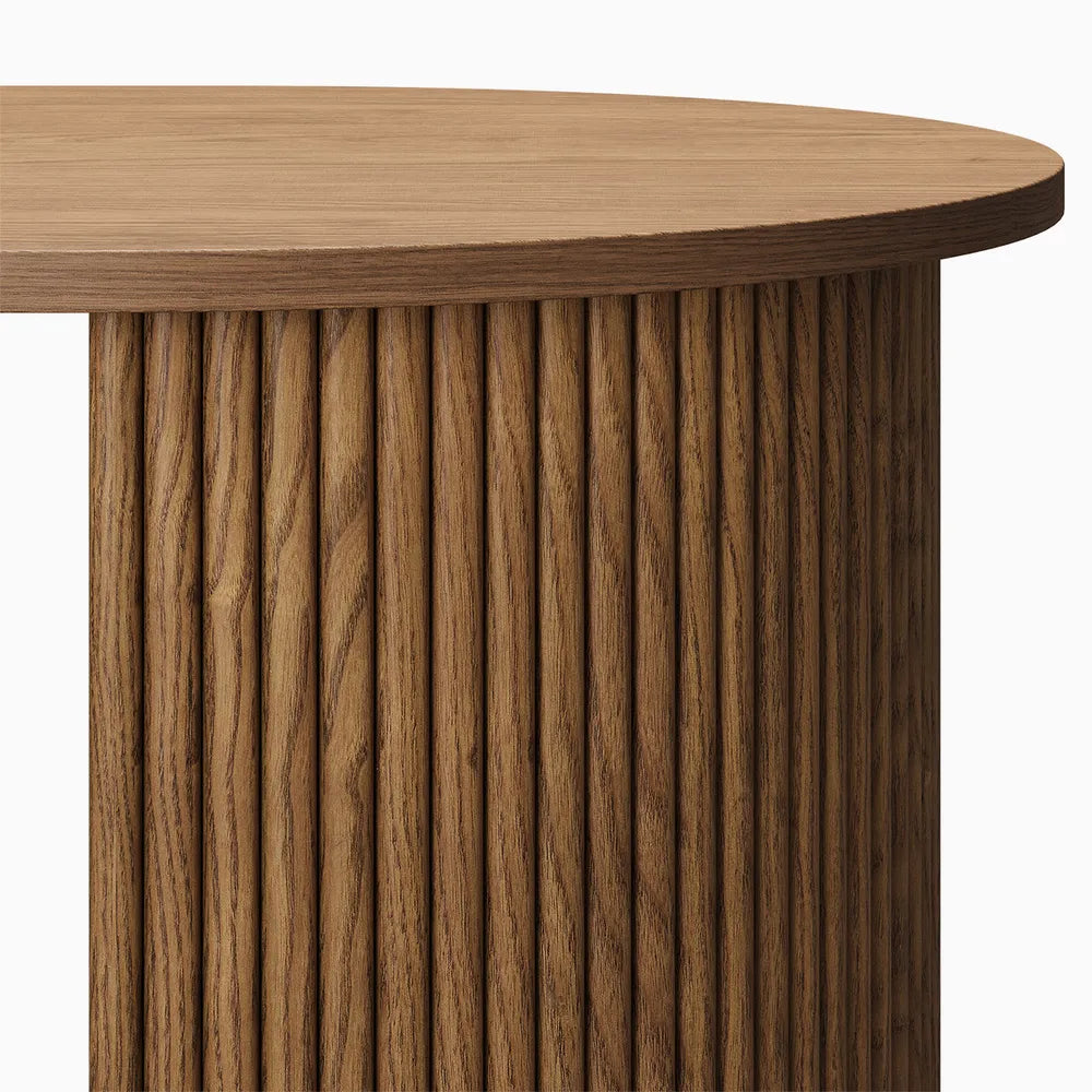 Close-up of fluted oval leg on wood coffee table, showcasing vertical ribbed detailing and a smooth rounded edge. 