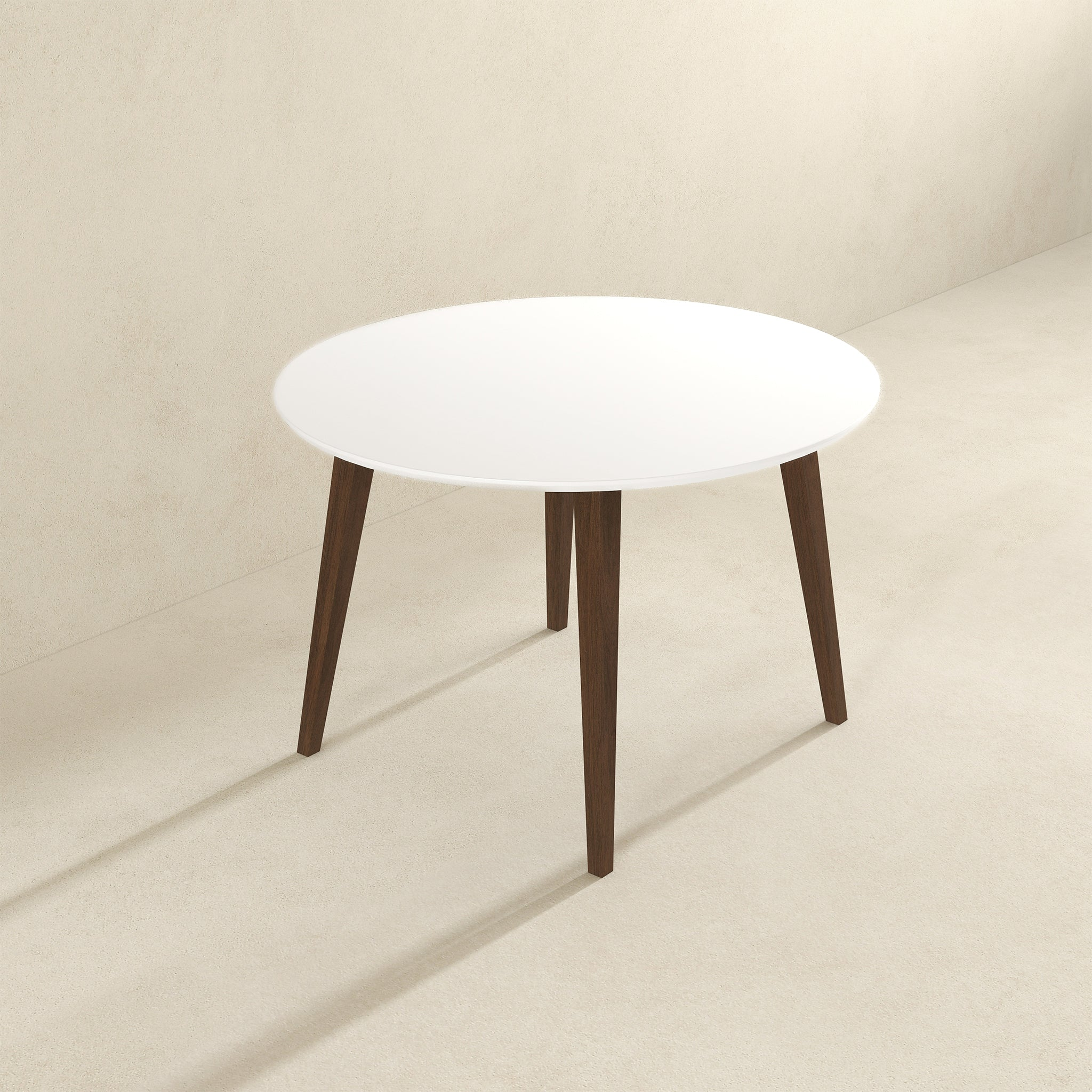 White round dining table, angled view showing the splayed walnut legs on beige background