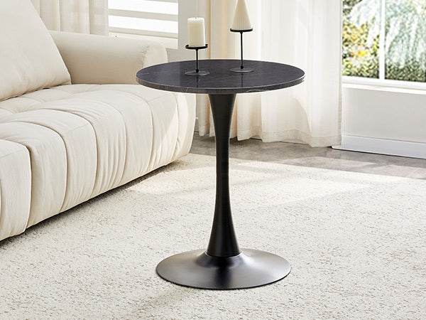 Black marble-look bistro table with a candle and cone candle by a cream sofa, three-quarter room view