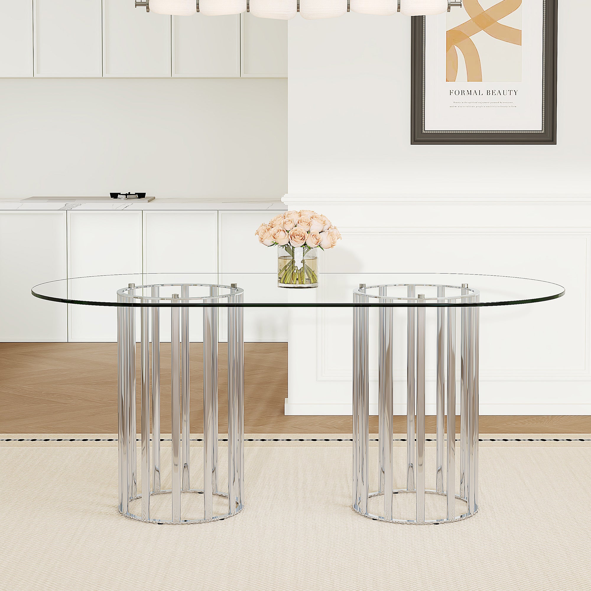 Oval glass dining table with silver double-column base in a bright dining room with framed wall art.