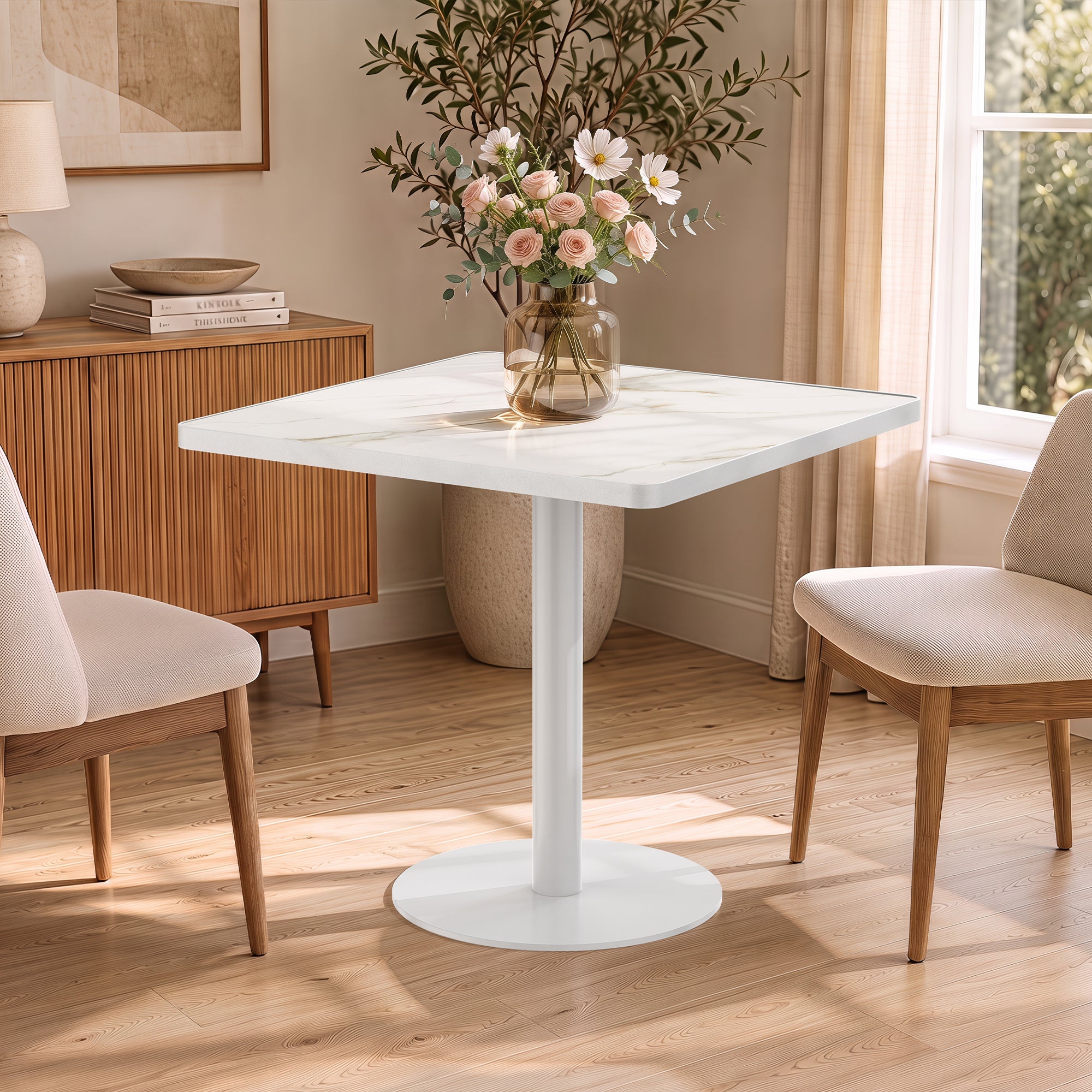White sintered stone square table in sunlit room with cream chairs and vase of flowers