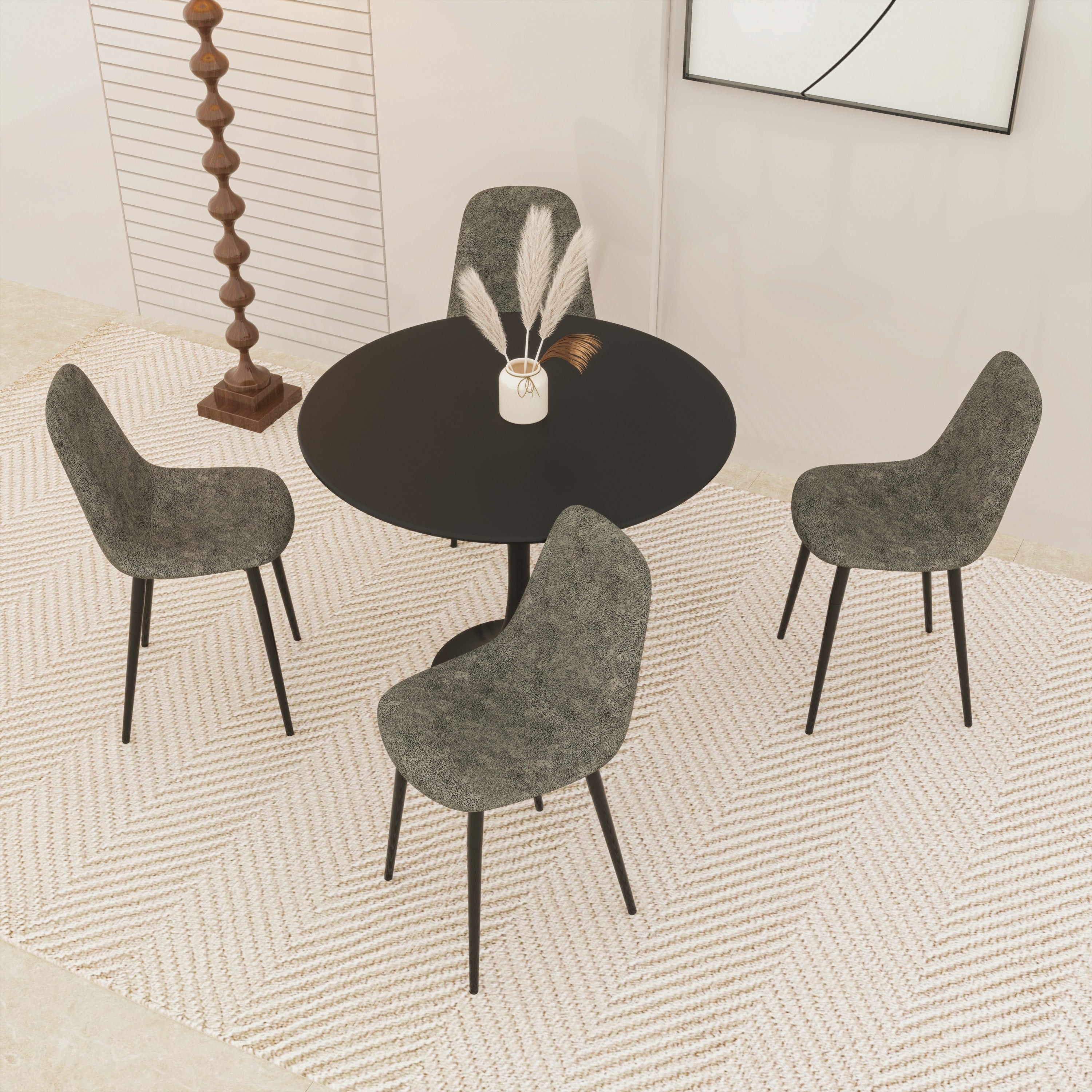 High angle of black round tulip dining table with four gray upholstered chairs on a woven rug