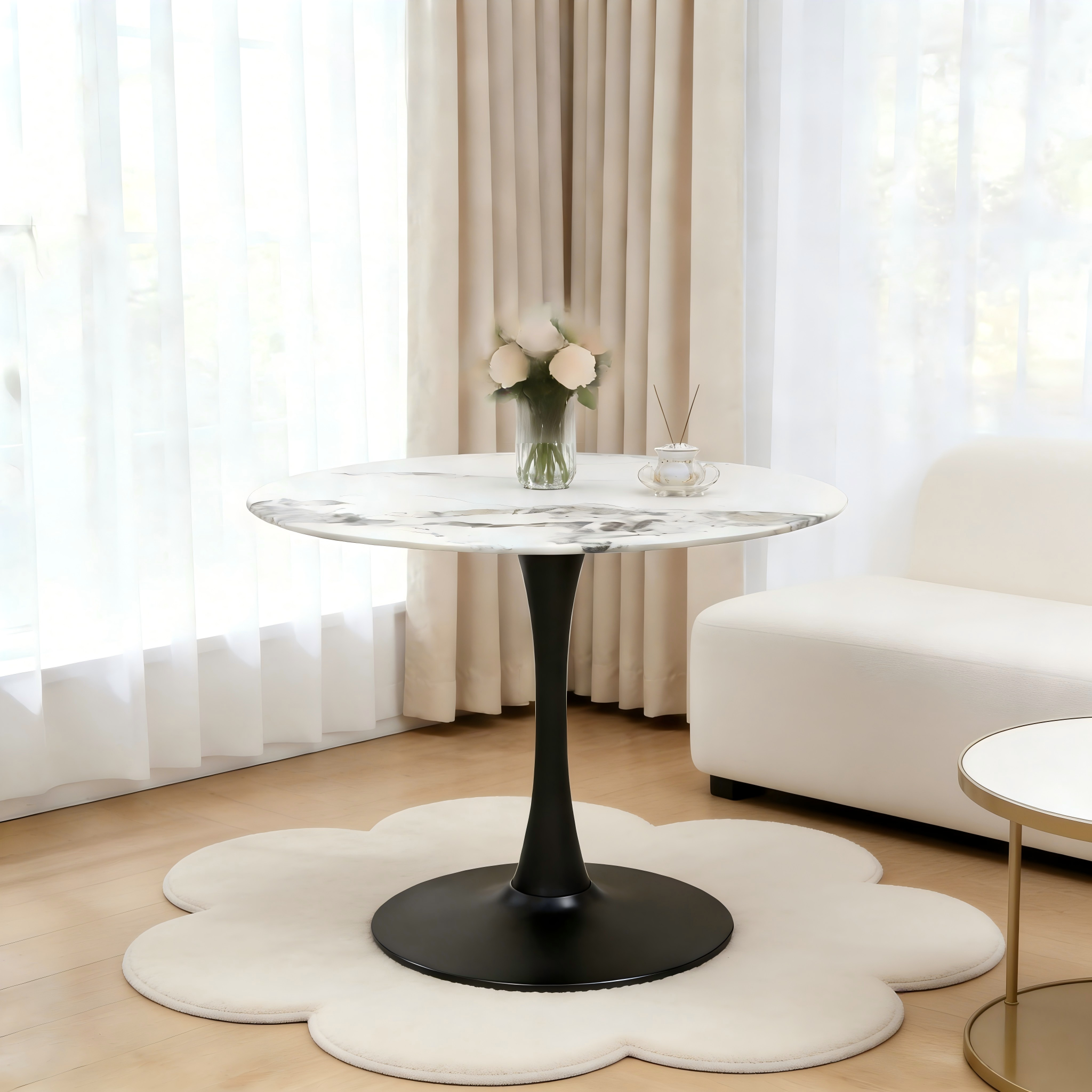White faux marble tulip table with black base in a styled room with a beige sofa