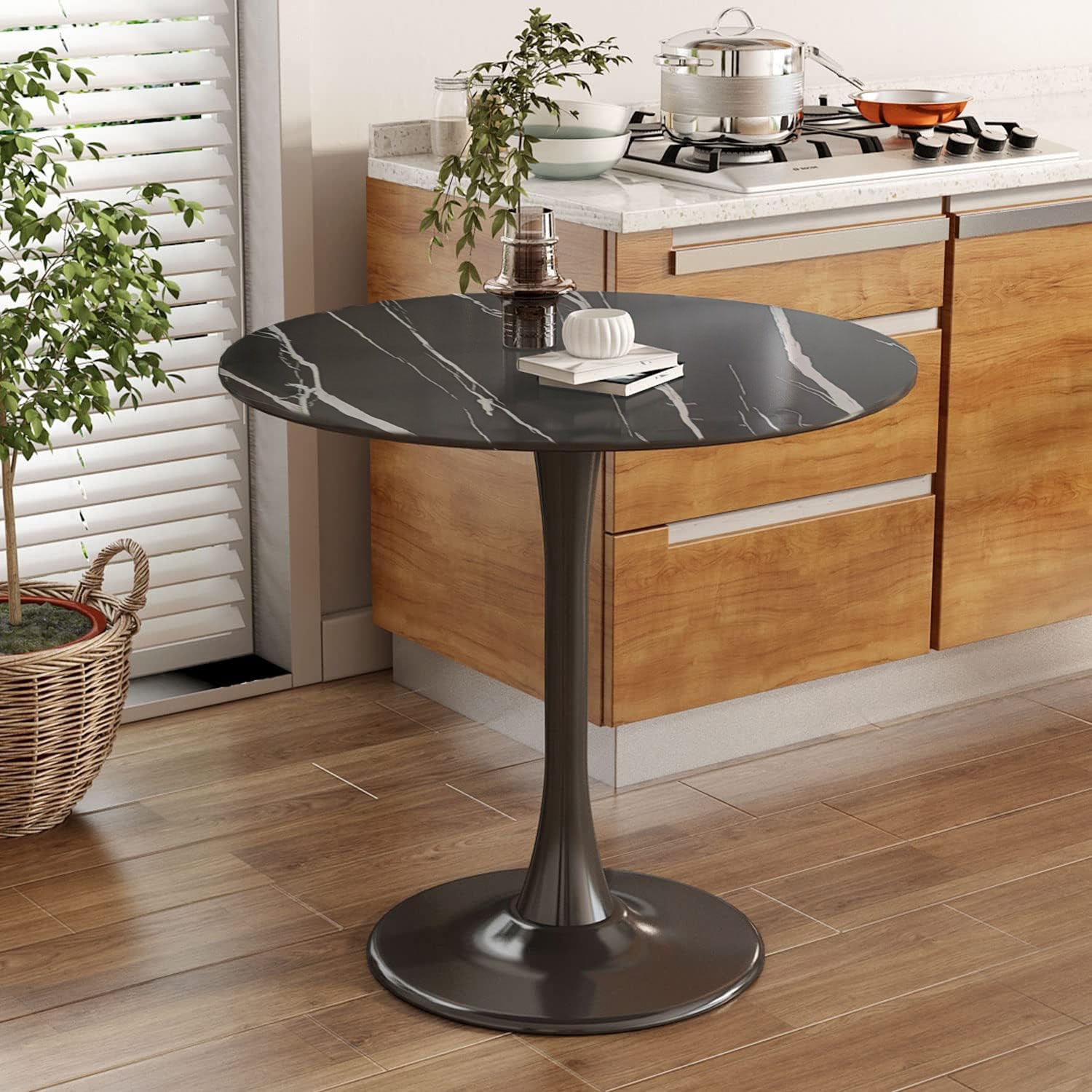 Black faux marble round bistro table with pedestal base in a wood kitchen, styled with books