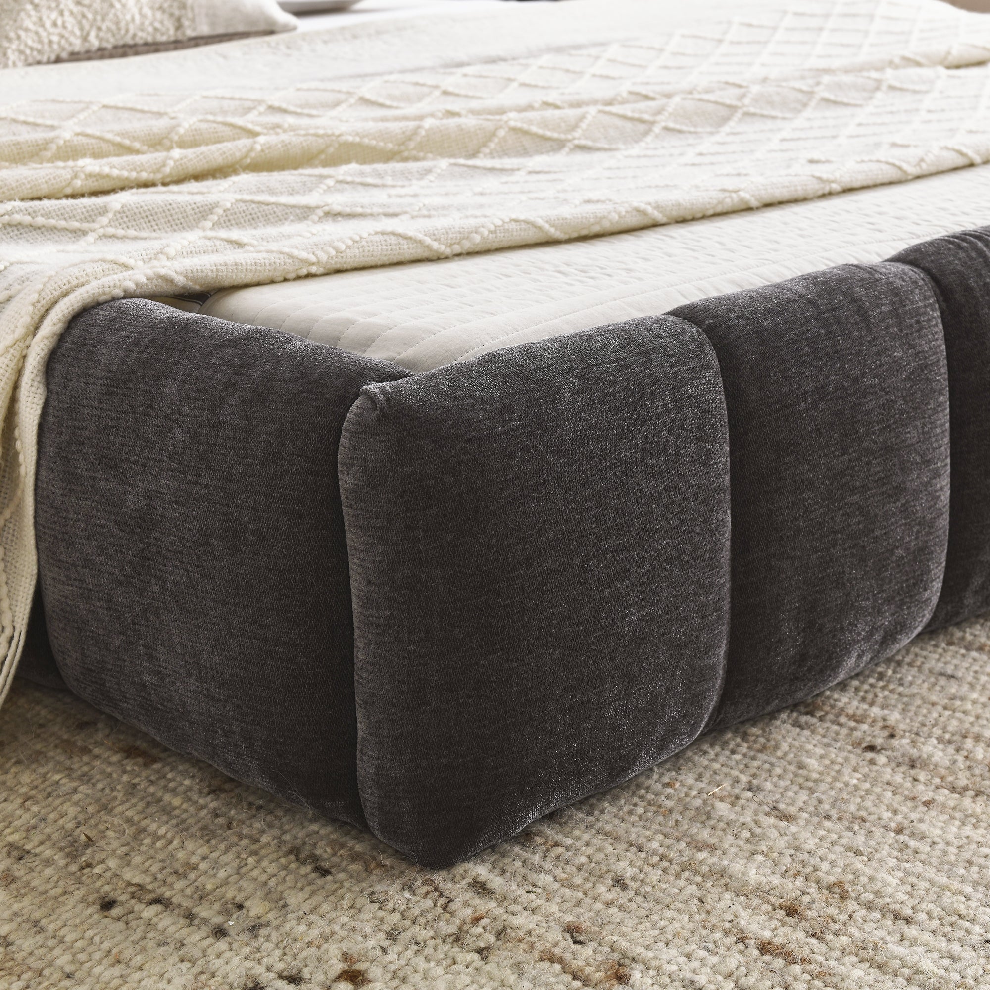 Close-up of the dark grey chenille bubble-tufted foot rail corner with white bedding #Color_Dark Grey