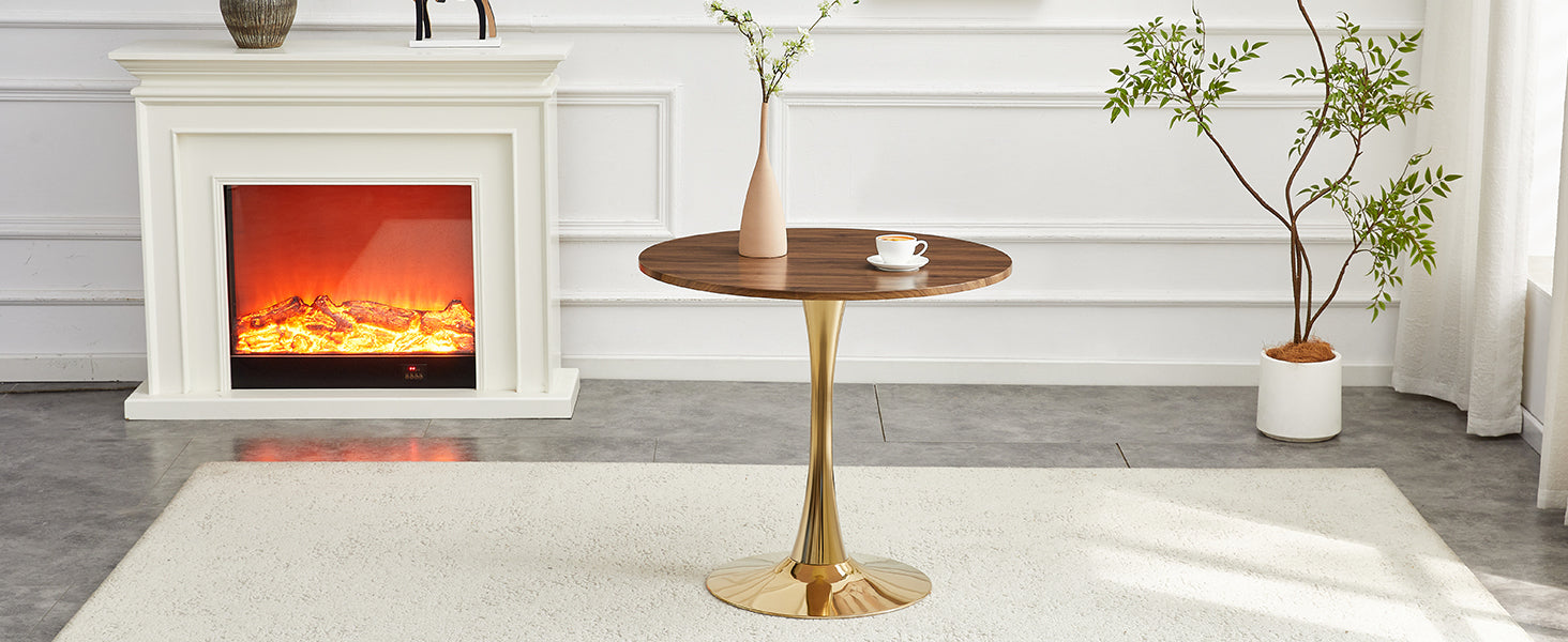 Walnut-top gold-base dining table in a sunlit room with a fireplace and potted tree, three-quarter view