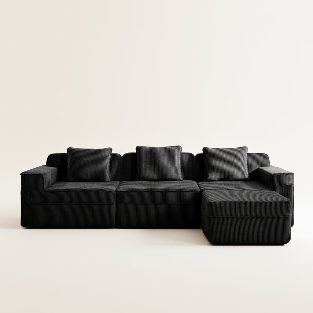 commercial photograph of the black boneless couch in corduroy with three seats and one ottoman showing the comfortable fabric and plush pillows