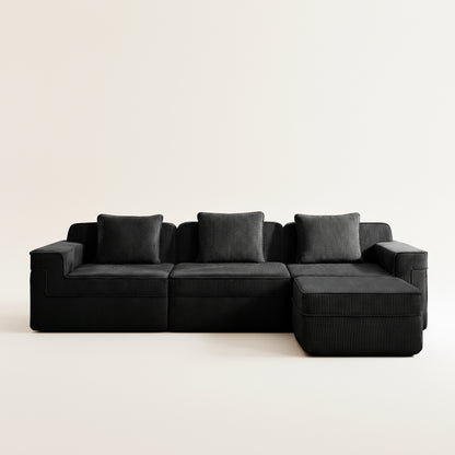 commercial photograph of the black boneless couch in corduroy with three seats and one ottoman showing the comfortable fabric and plush pillows
