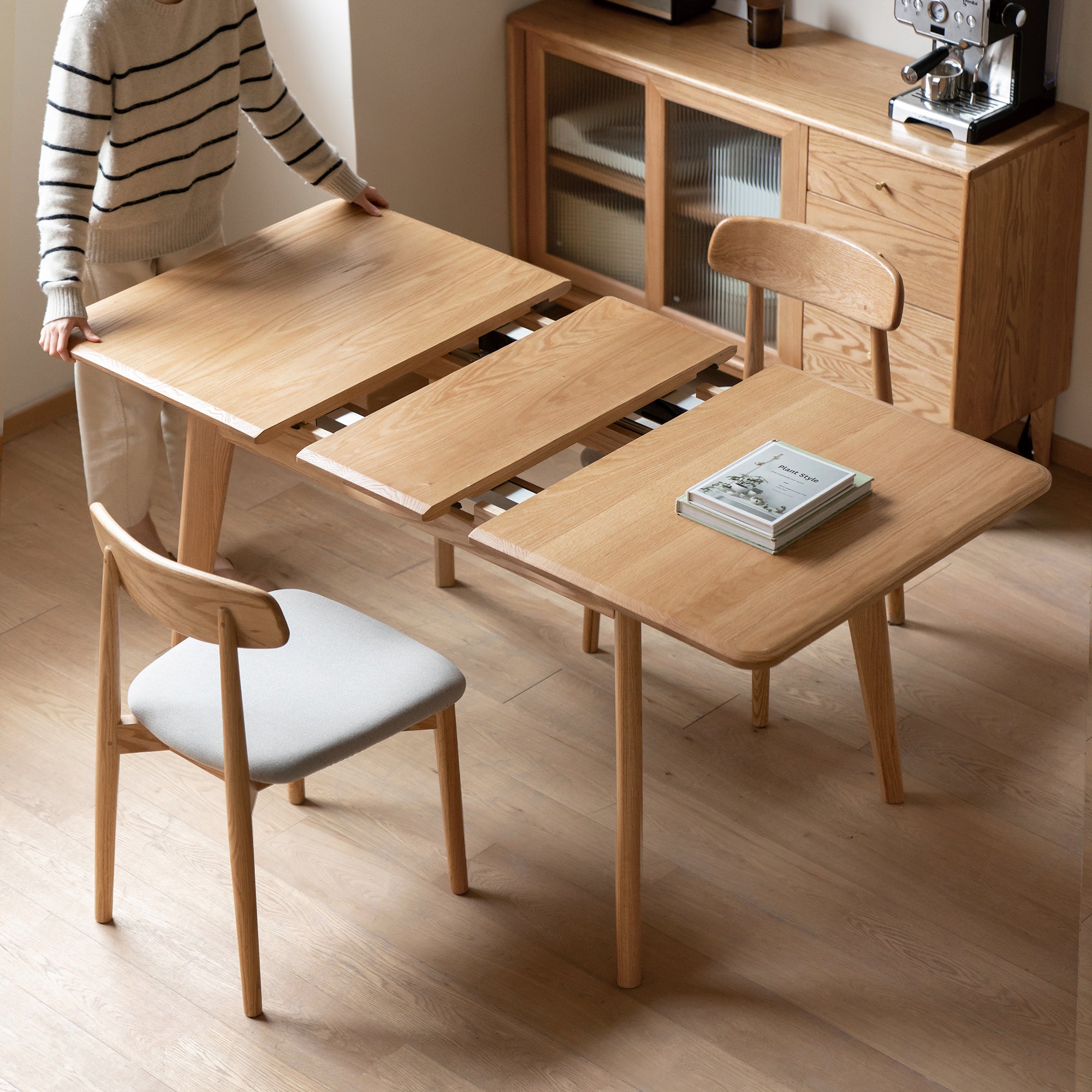 Natural oak dining table opened wide with the extension slides exposed at the center