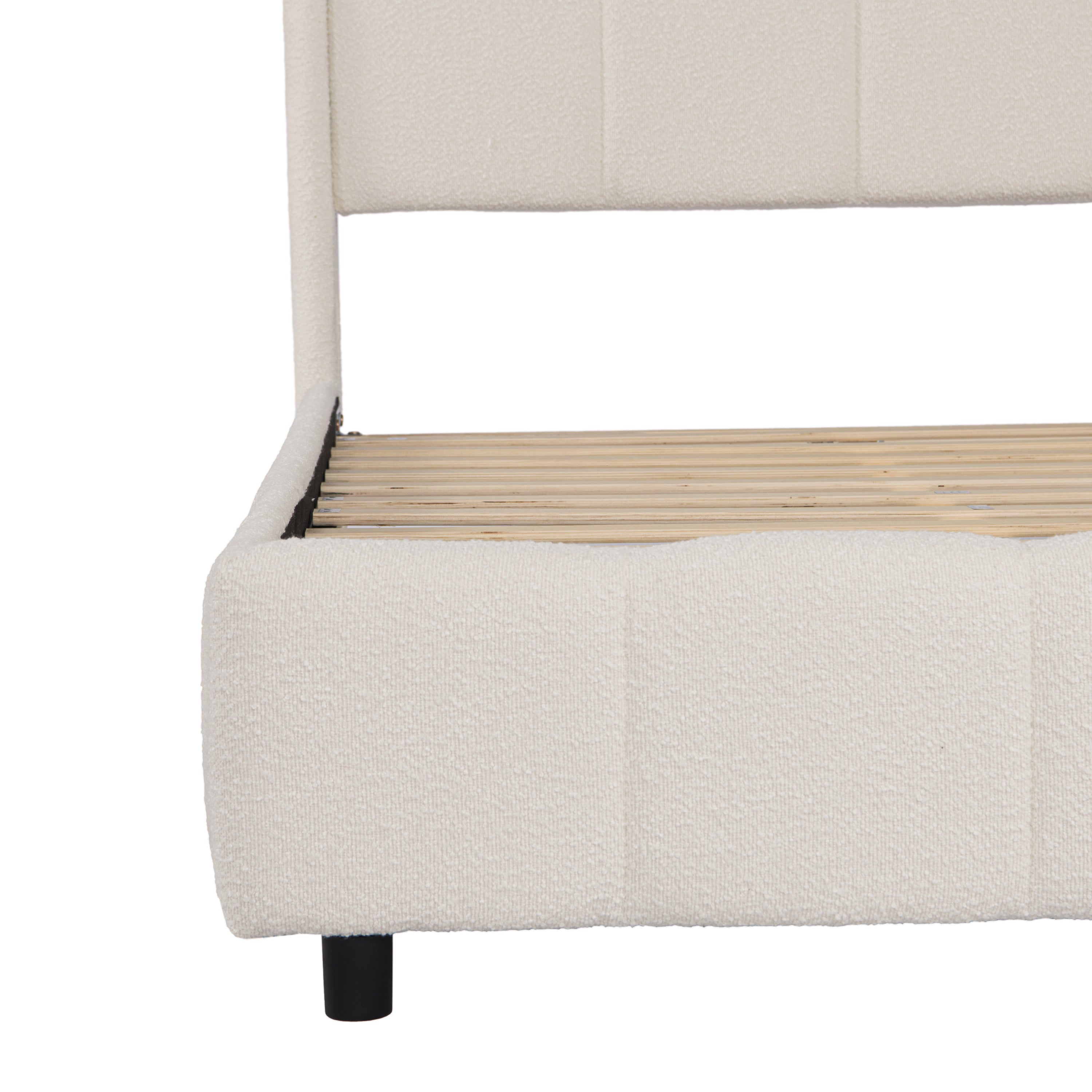 Close-up of footboard corner showing beige bouclé fabric and black support leg