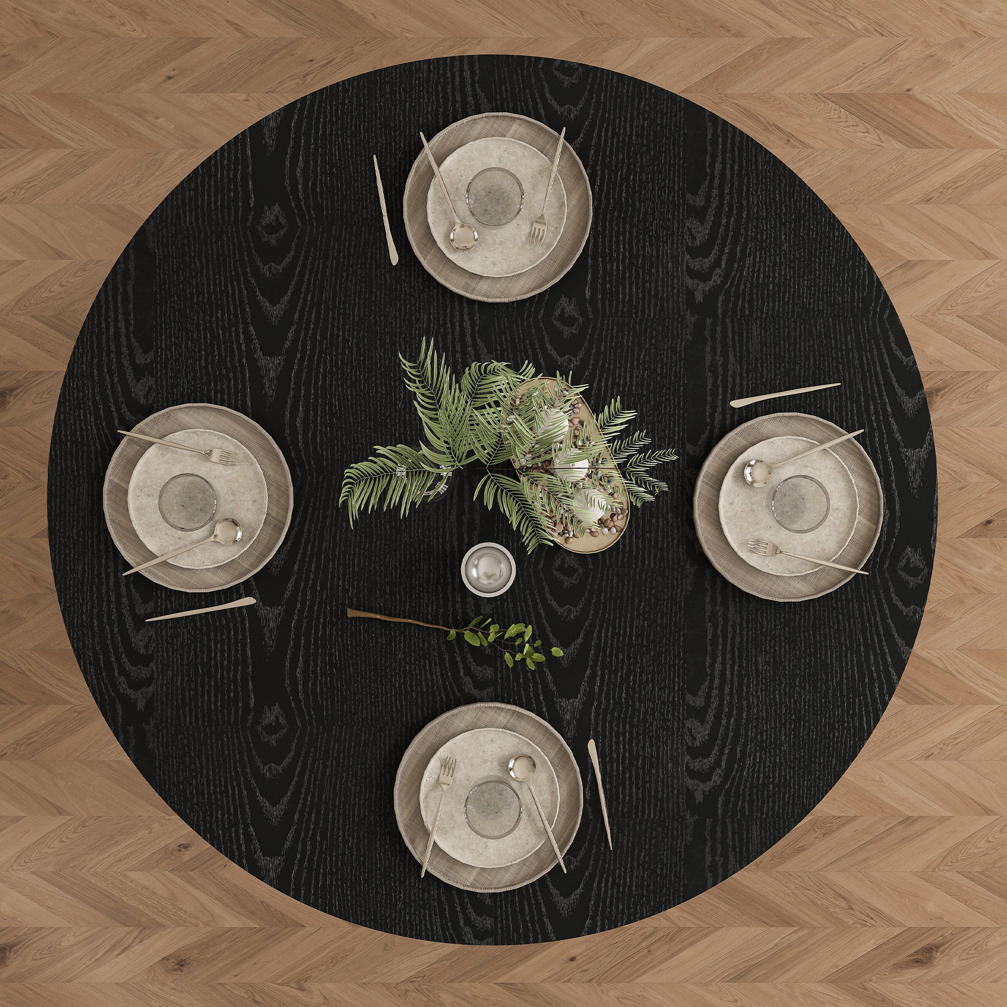 Overhead view of black round dining table set for four on a herringbone wood floor