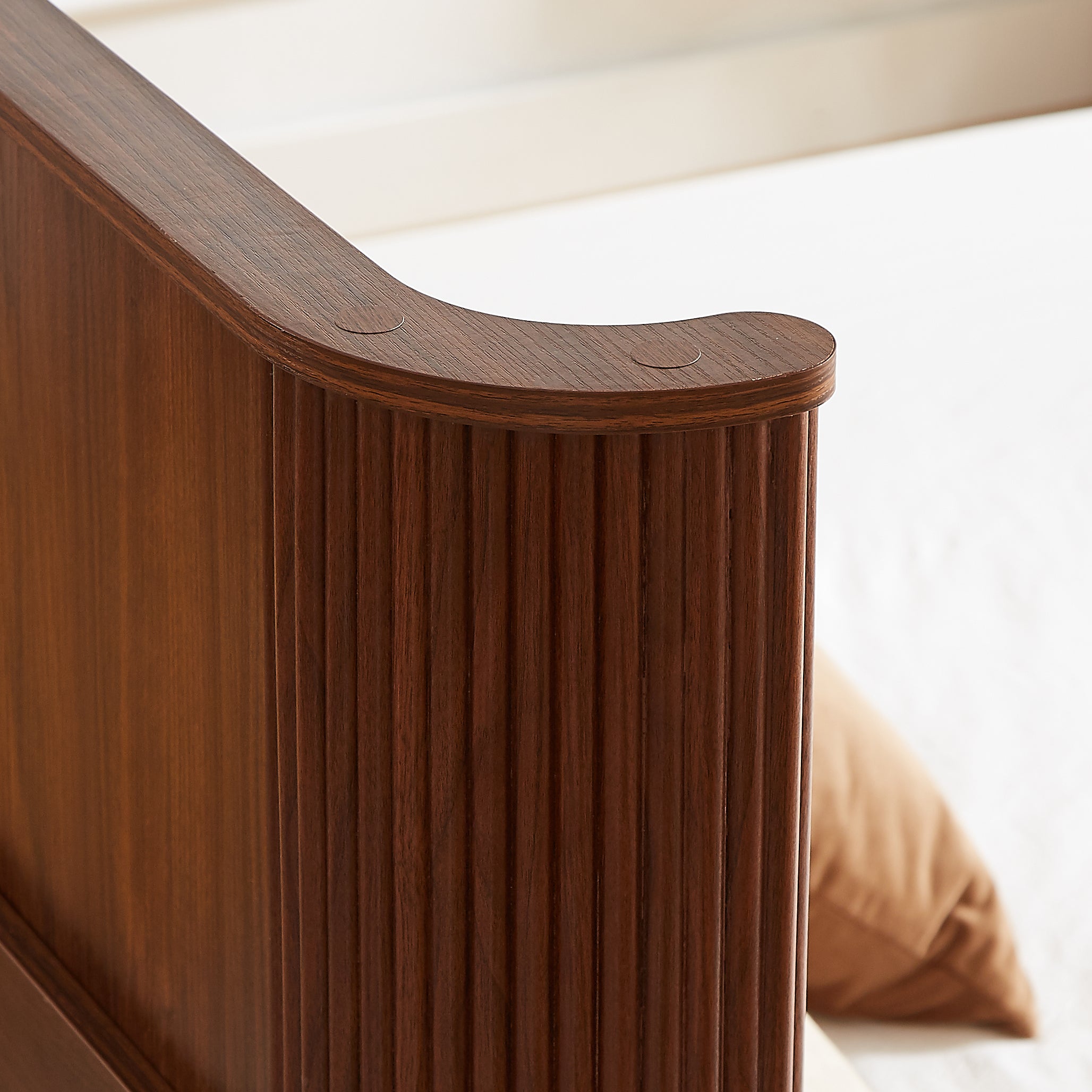 Detail of the rounded, smooth curved top corner of the walnut fluted headboard #Color_Walnut