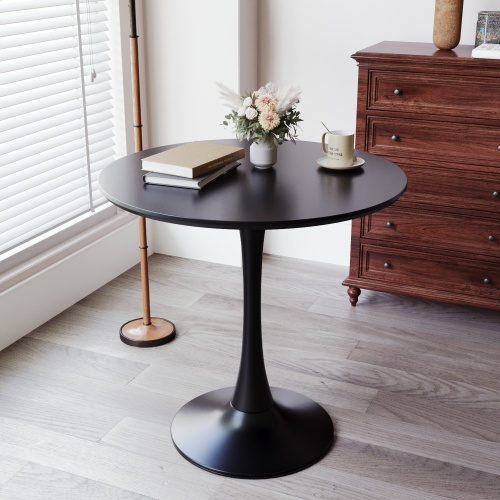 Round black tulip table with books and flowers by a window and wood dresser