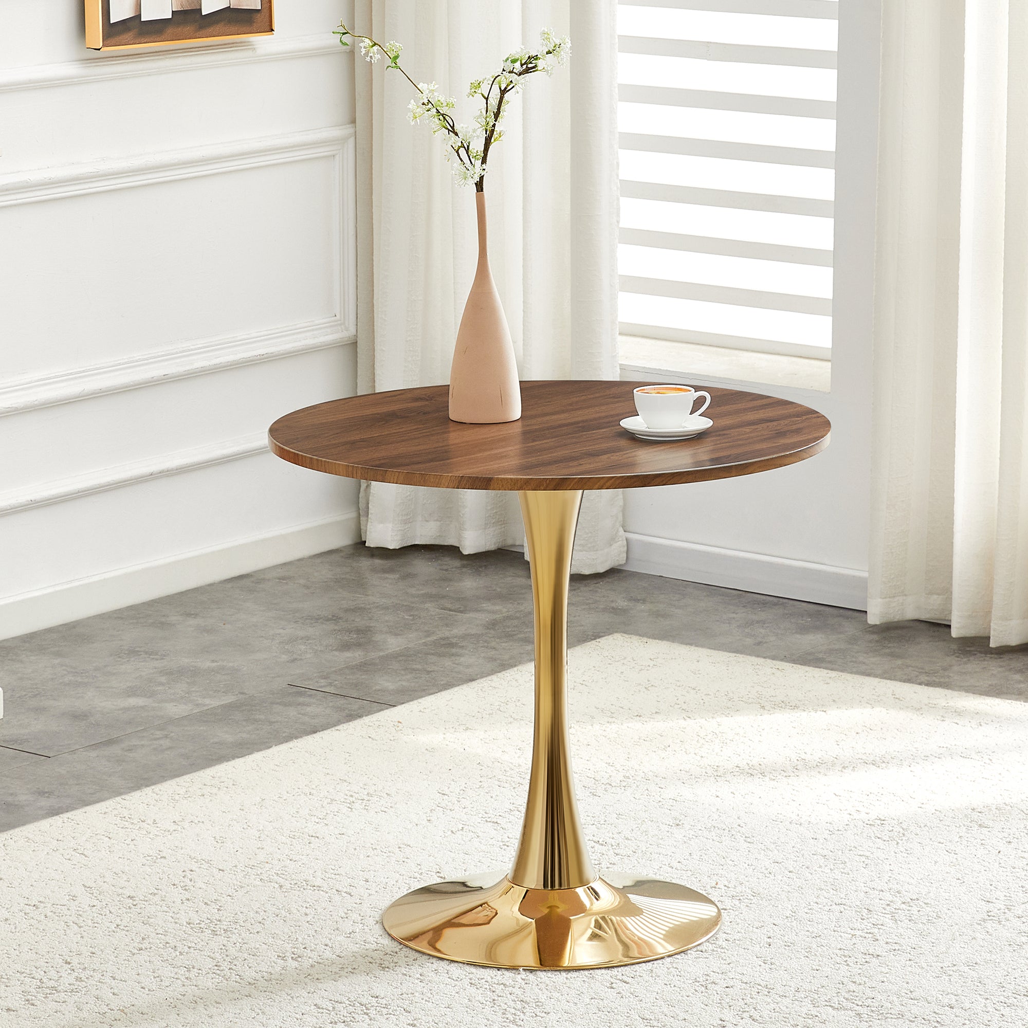 Walnut round dining table with gold pedestal styled by a fireplace with a vase and coffee, front view