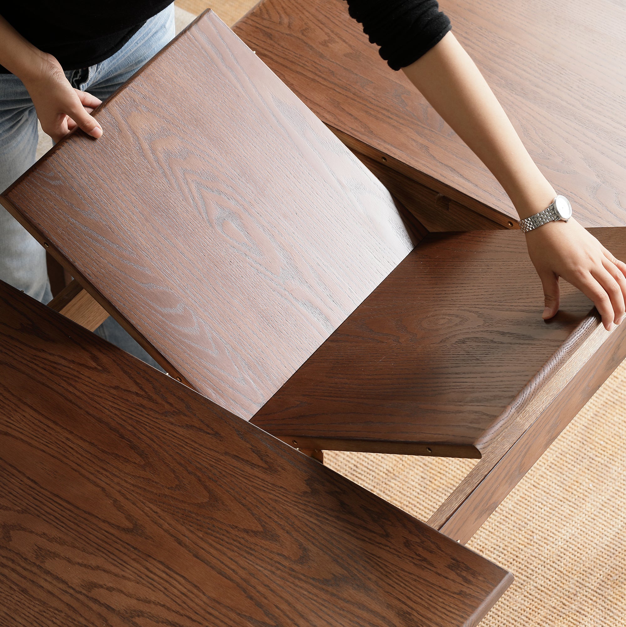Top-down view of hands opening the table to add the center butterfly leaf