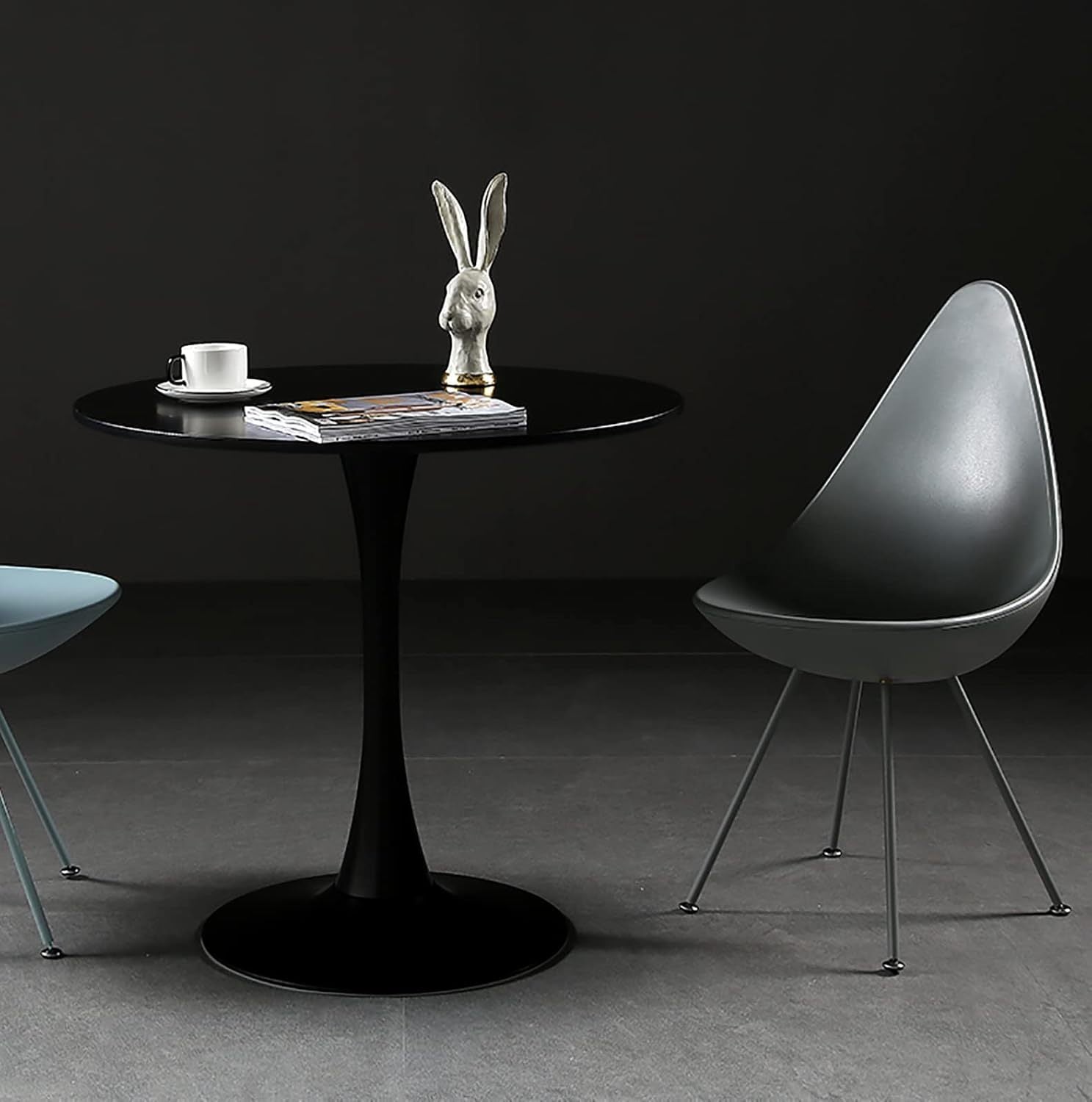 Round black tulip table with a rabbit figurine and coffee cup in a dark styled room