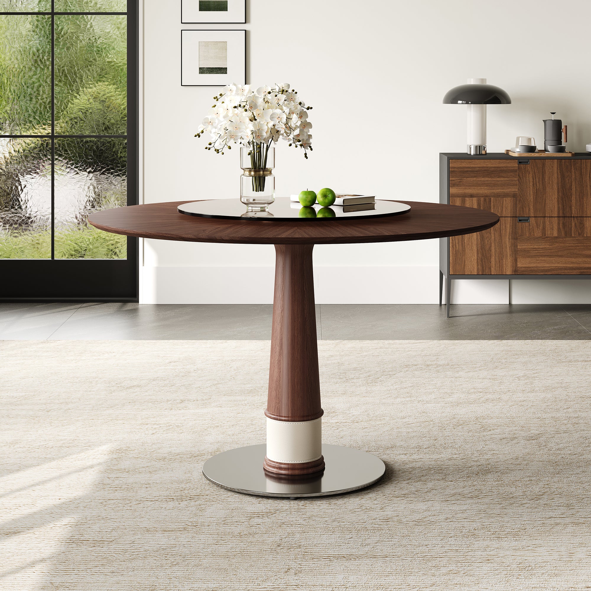 Walnut round dining table with a glass turntable and tapered column base in a styled room, three-quarter view