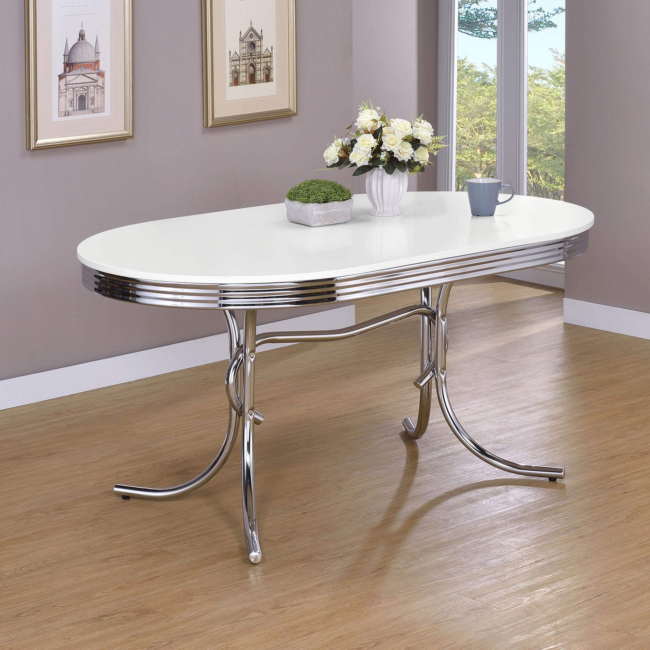 Styled dining room with the white and chrome retro oval table holding flowers and a mug