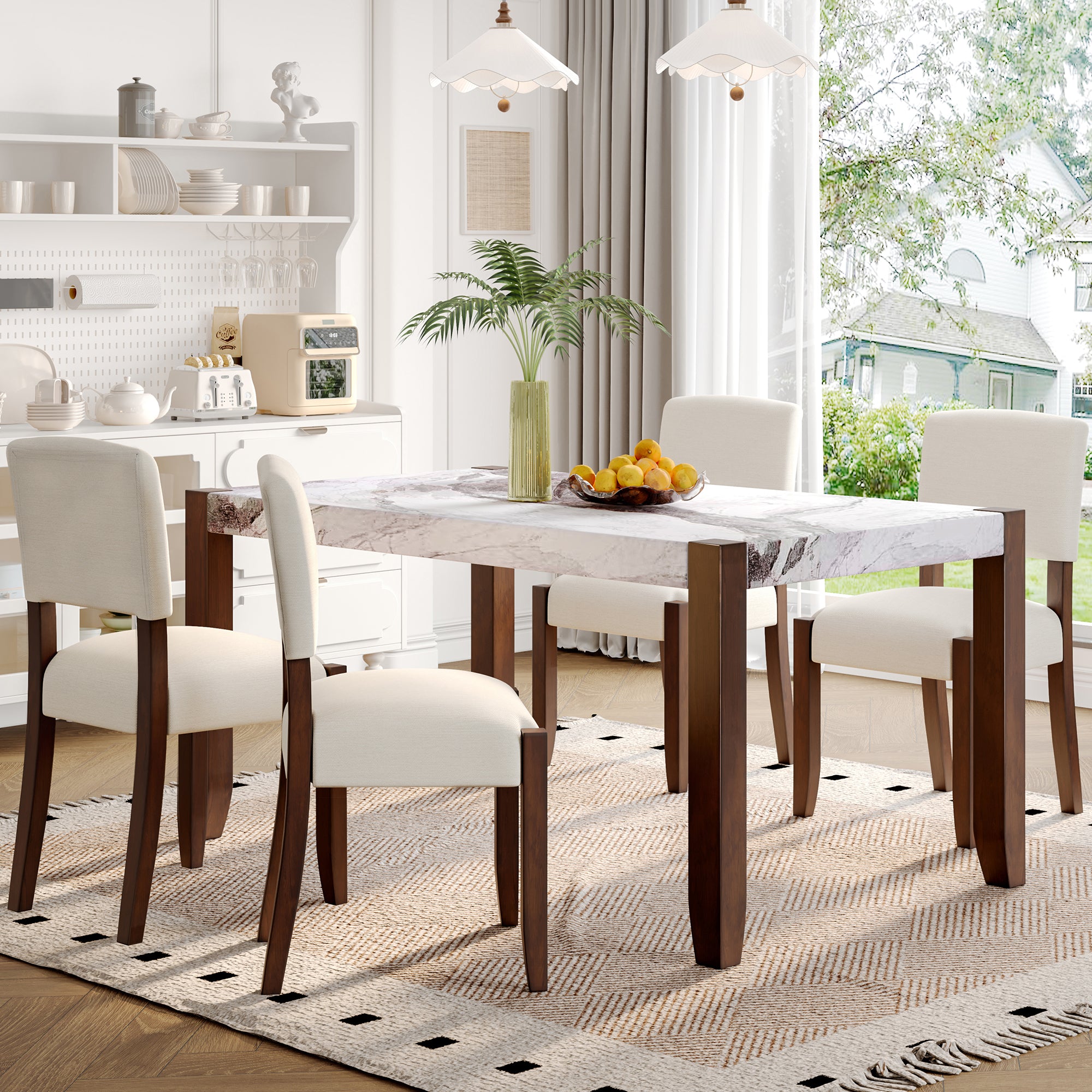 Faux marble dining table with cream chairs and a bowl of lemons in a bright farmhouse kitchen