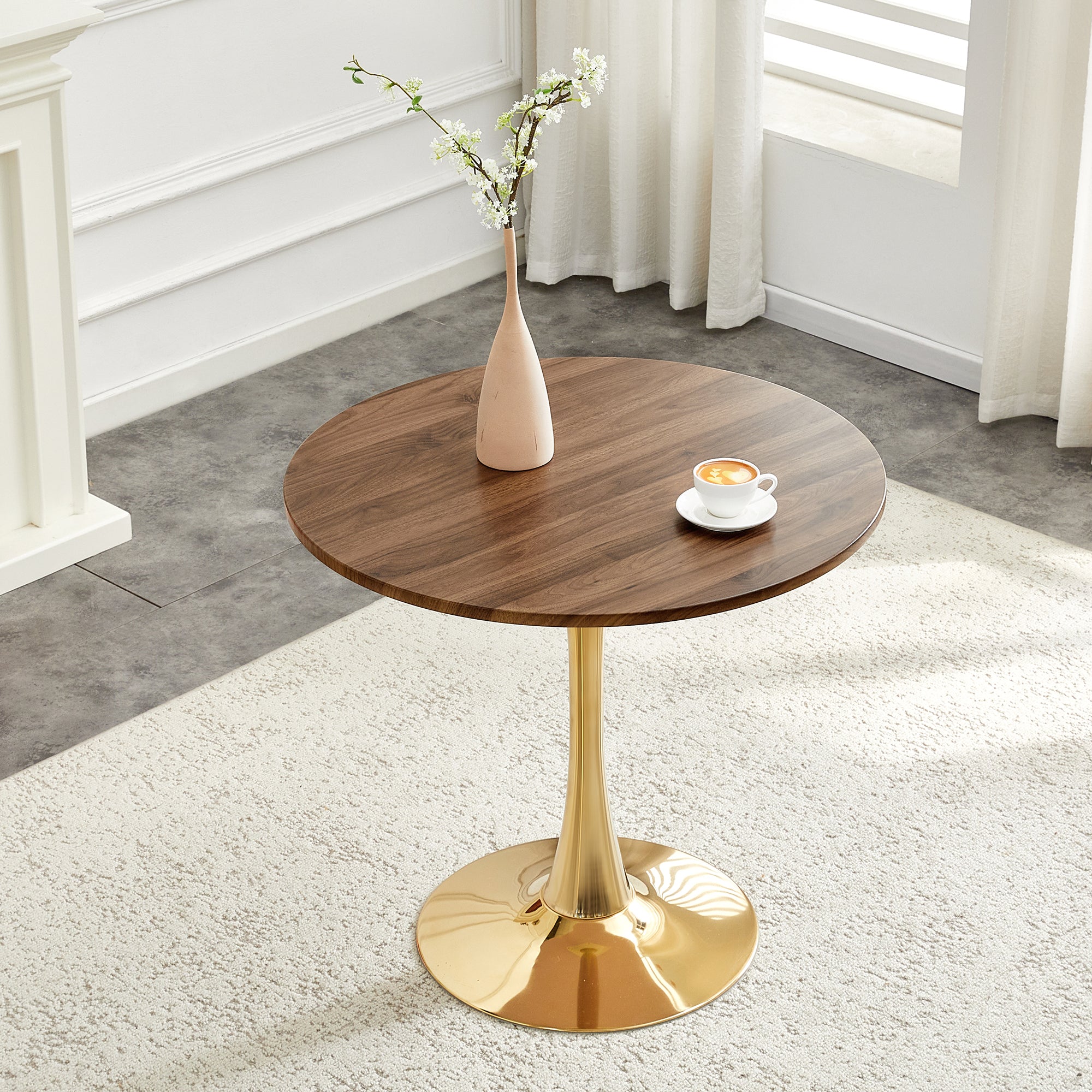 Walnut-top gold-base dining table with a vase and coffee cup by a window, three-quarter view