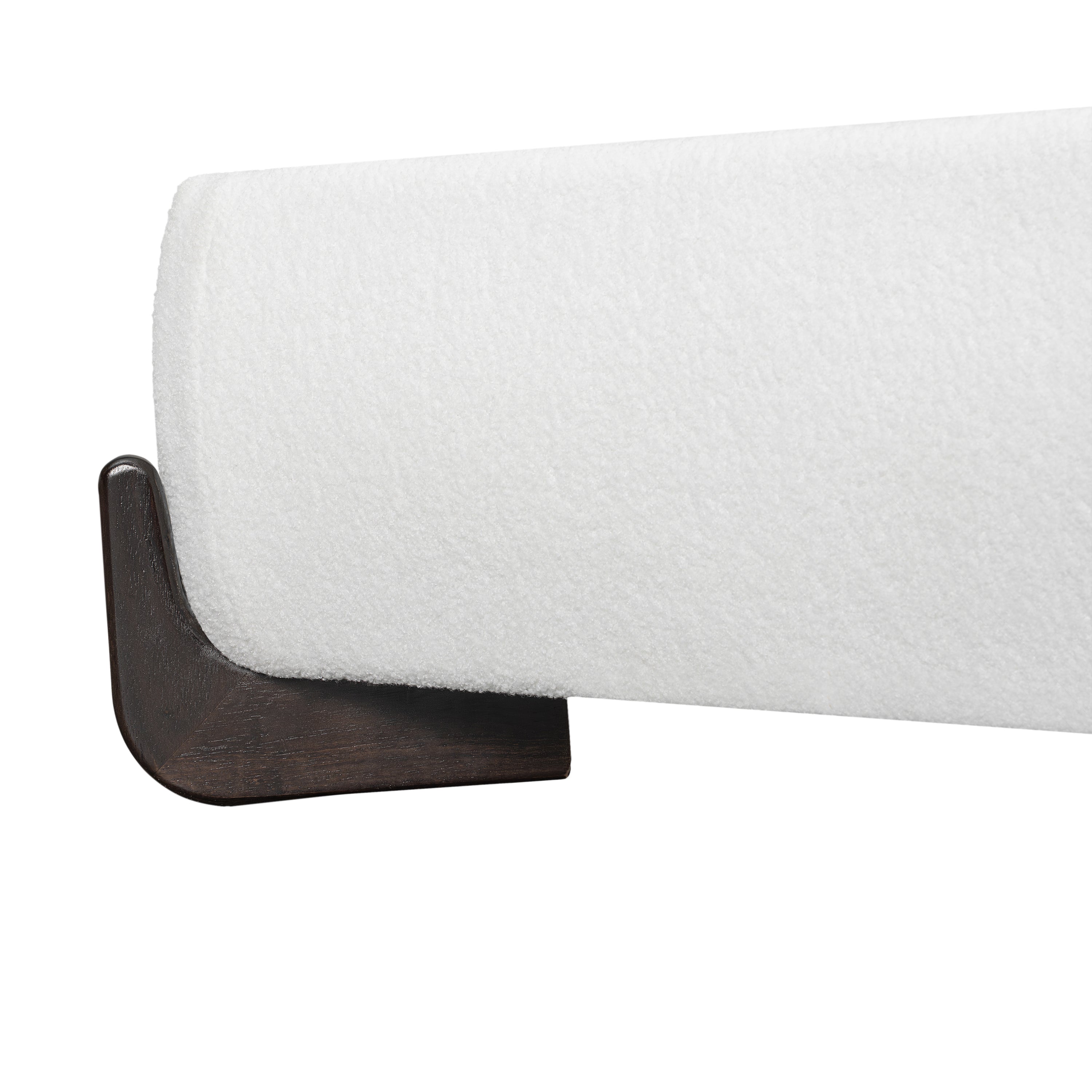 Close-up of dark brown solid wood sled leg on white bouclé bed frame
