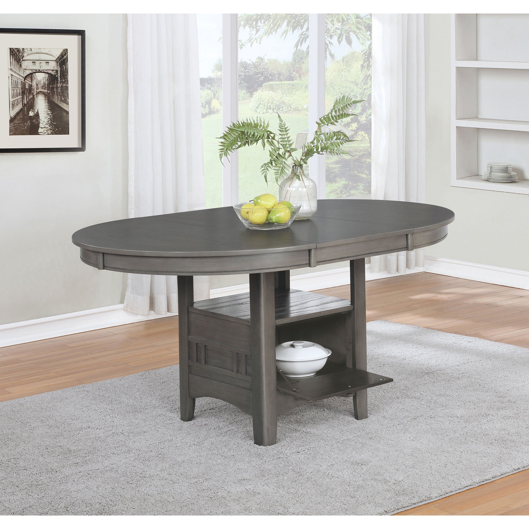 Grey oval dining table styled with a fern and lemons by a window