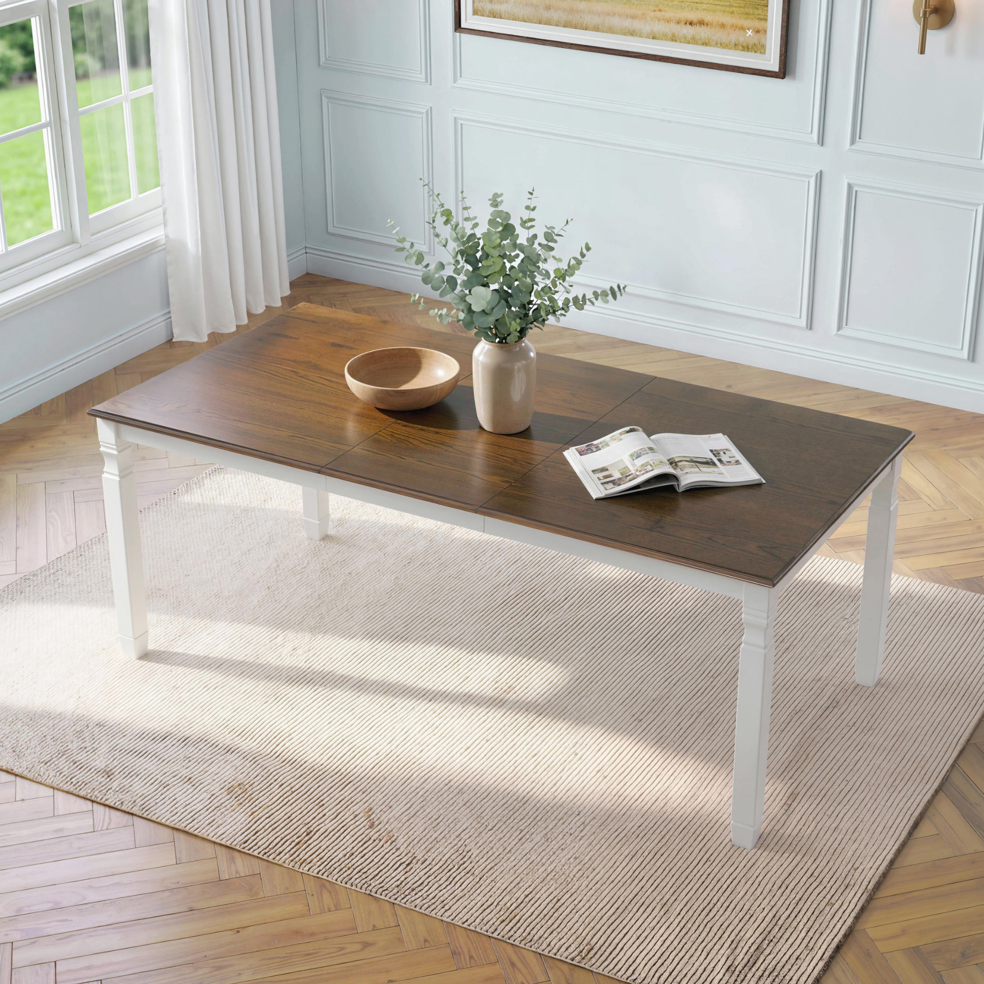 Overhead angled view of brown oak veneer farmhouse extendable dining table with white legs in a styled dining room