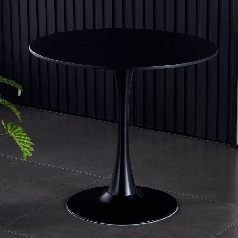 Round black tulip table against a black slatted wall on gray tile flooring