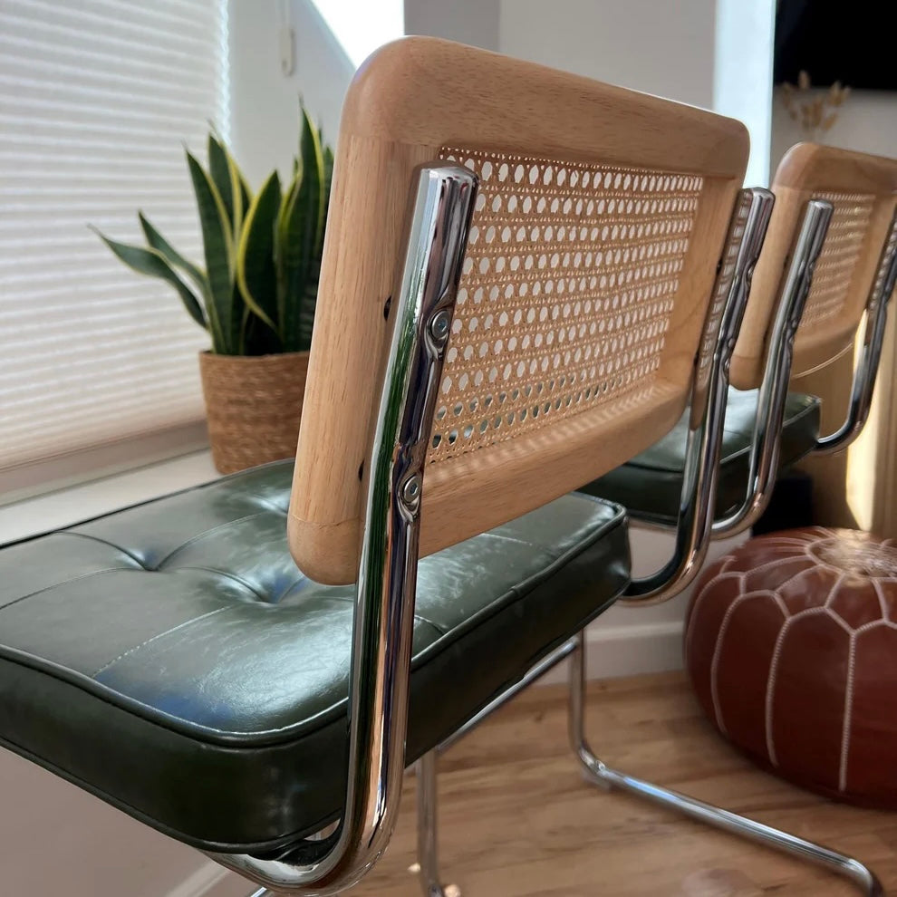 closeup of solid wood and rattan counter stool backrest with green vegan leather seat and stainless steel frame
