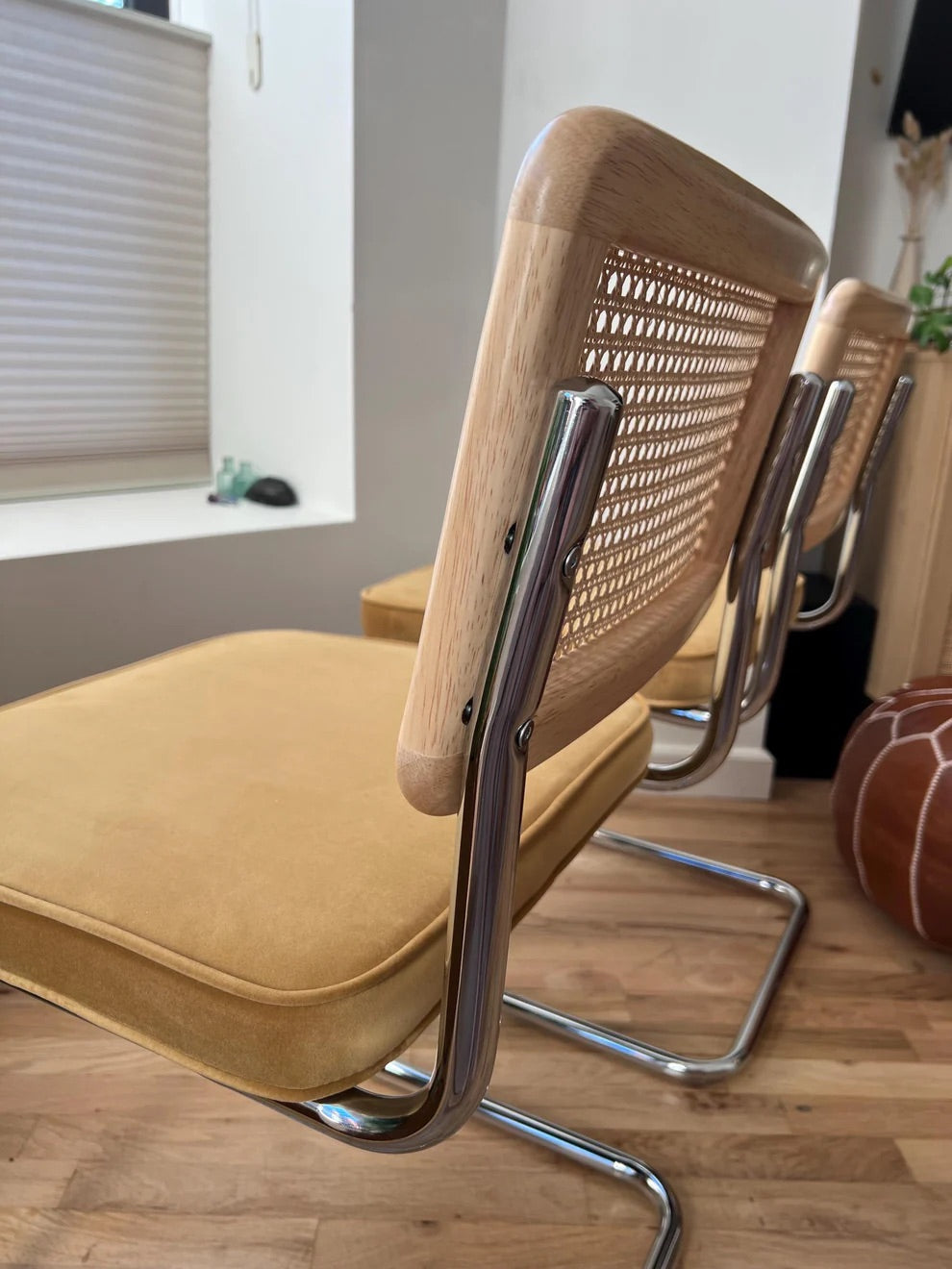 closeup of woodgrain on dining chairs with stainless steel frame and natural rattan with yellow velvet seats