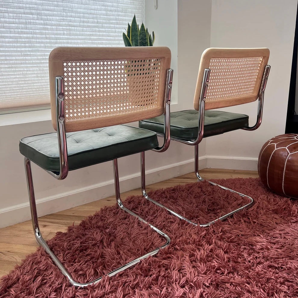 back of cantilever green vegan leather dining chair with solid wood backrest with natural rattan and stainless steel frame 