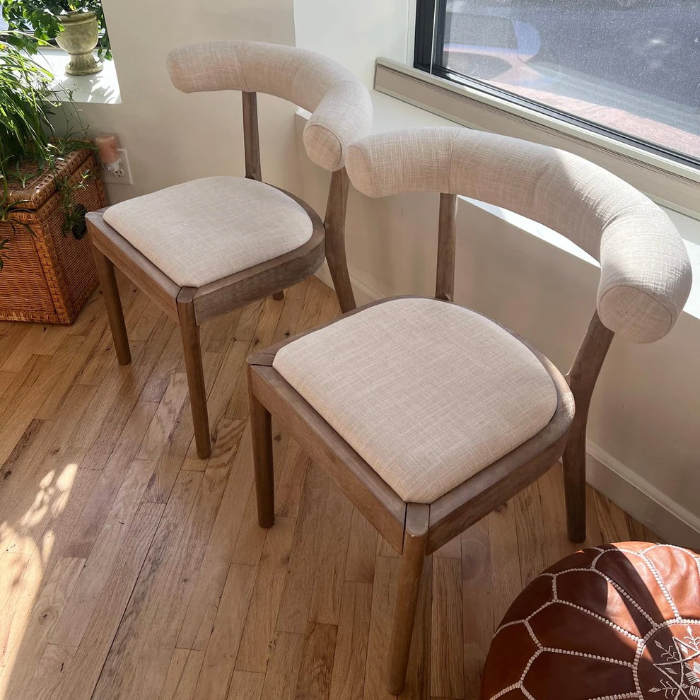side overview of solid wood dining chairs with ergonomic back rests and white linen upholstery 
