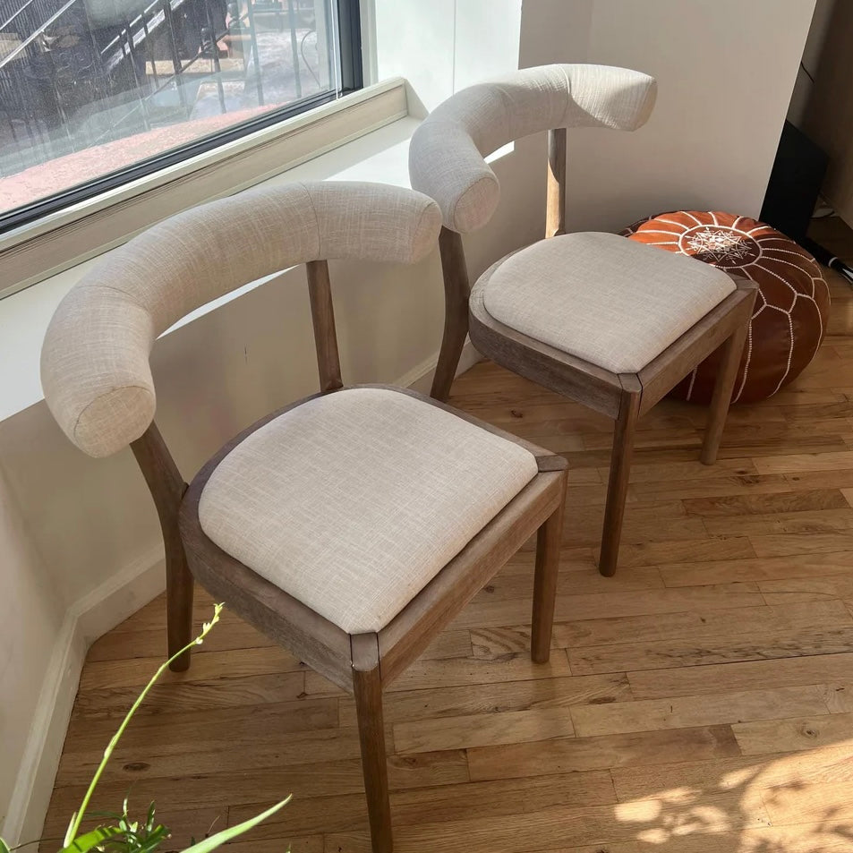 side quarter overview of white linen and solid wood dining chairs for circular table