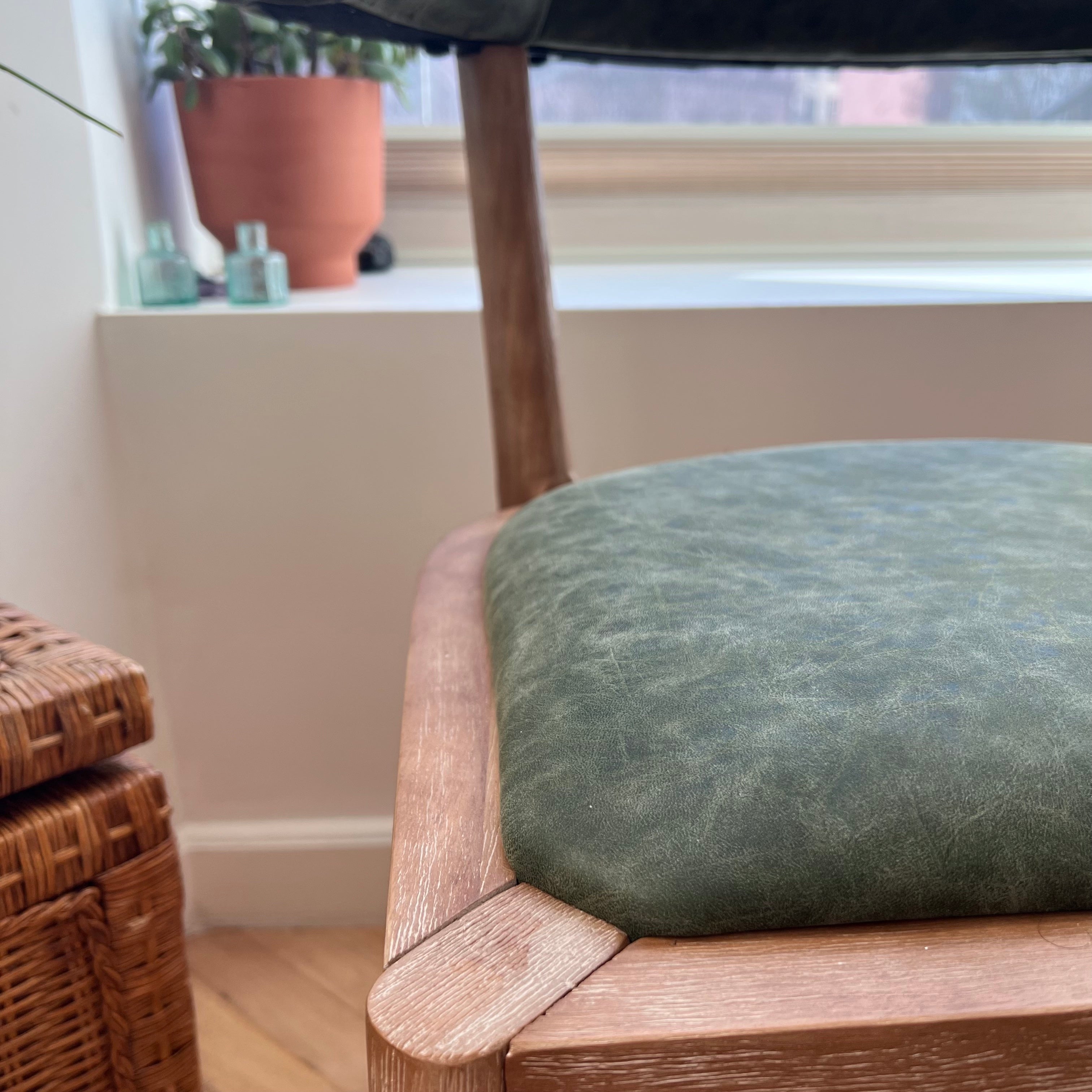 close up of solid wood dining chair with woodgrain patterns showing and green vegan leather seat texture