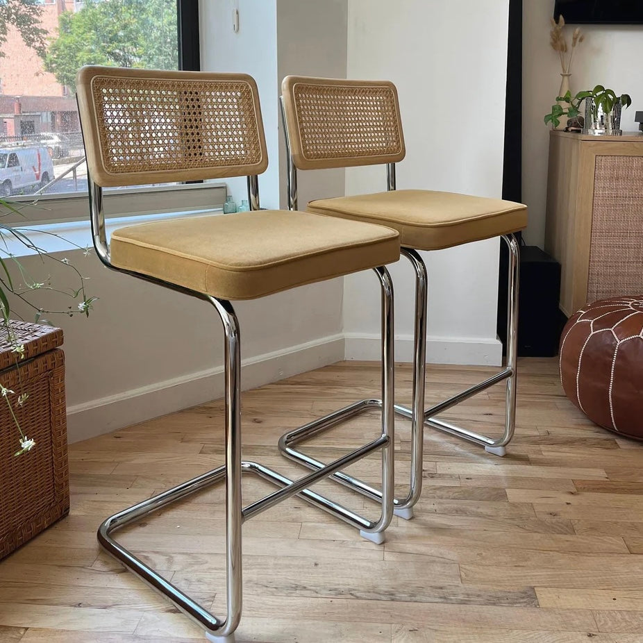 pair of cantilevered counter height bar stools with 26 inch seat height and stainless steel frame with mustard yellow seats 